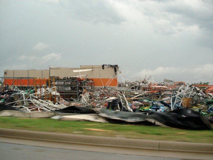 Debris from the tornado covers a street block, damaged building in the background.